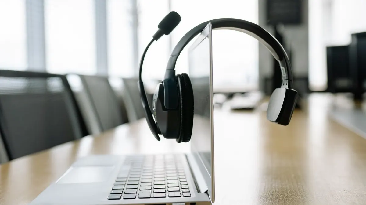 Laptop elegante con un headset inalámbrico en un entorno de oficina moderno y luminoso.