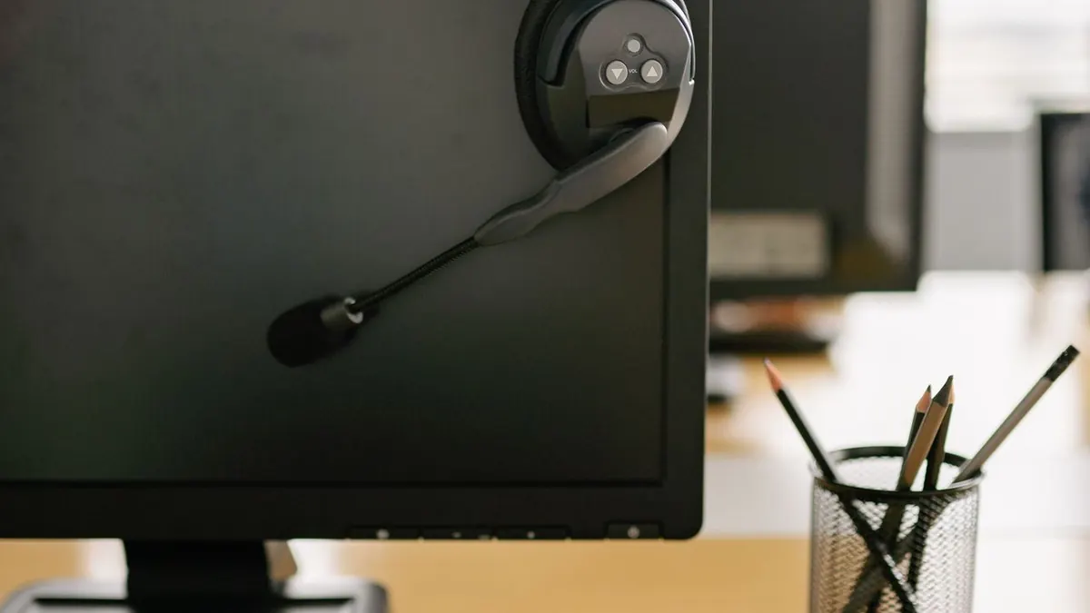 Espacio de trabajo limpio y organizado con un monitor de computadora y un auricular en un entorno de oficina moderno.
