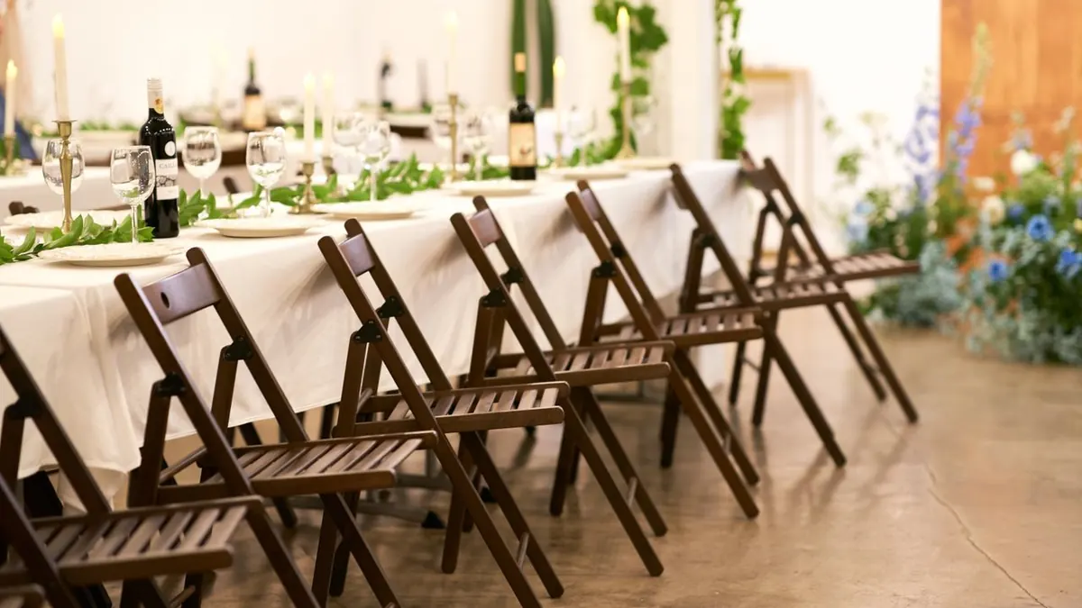 Mesa de banquete bellamente decorada con acentos florales y sillas de madera.