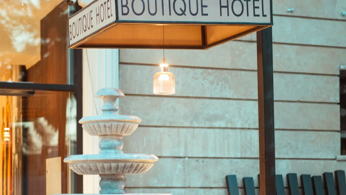 Elegante entrada de un hotel boutique en Bagdad con una fuente de agua clásica y exuberante vegetación.