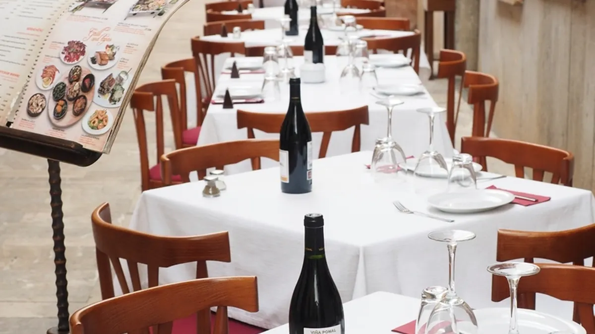Mesa larga preparada en un restaurante con botellas de vino