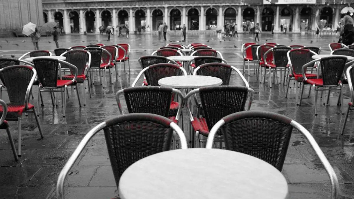 Mesas y sillas vacías de una terraza de restaurante en blanco y negro