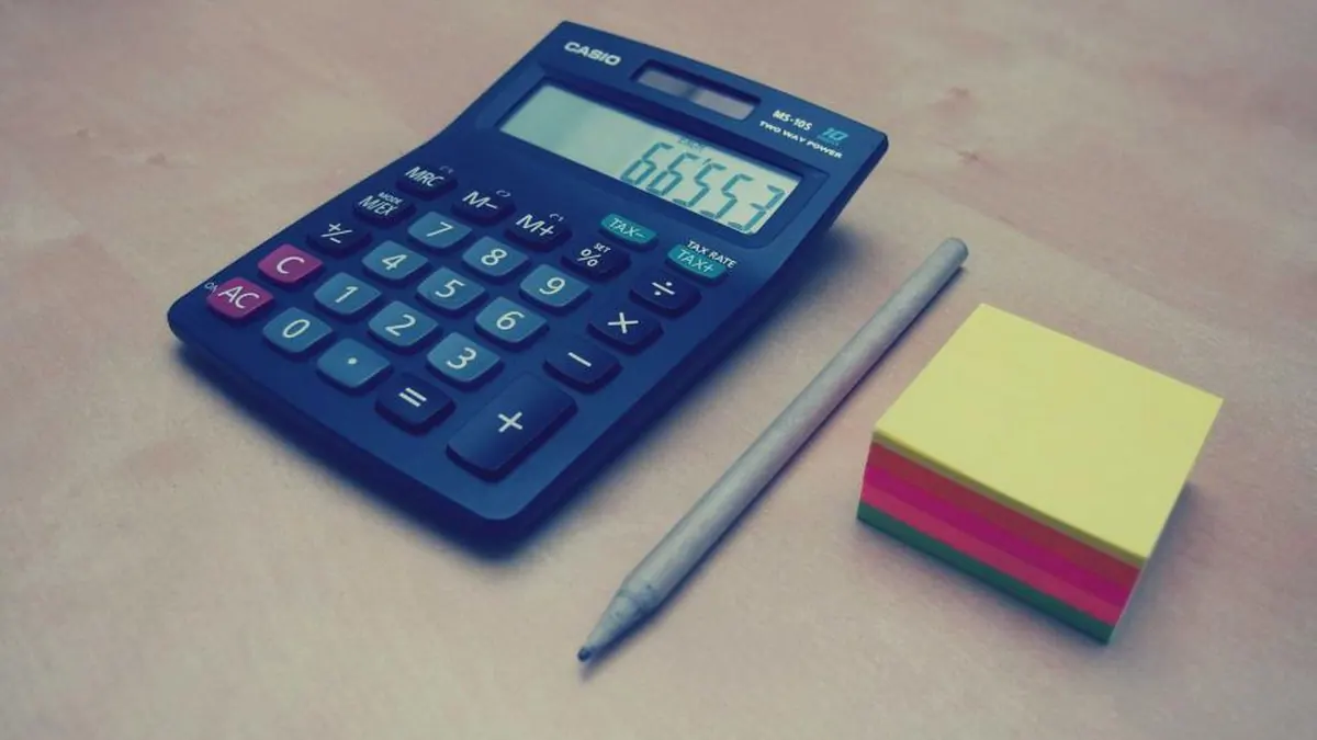 Calculadora azul con un bolígrafo y notas adhesivas