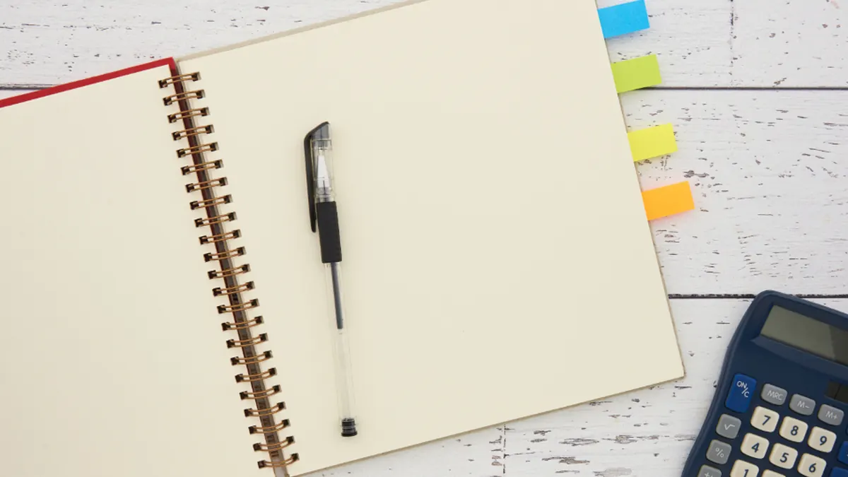 Libreta abierta con un bolígrafo y una calculadora