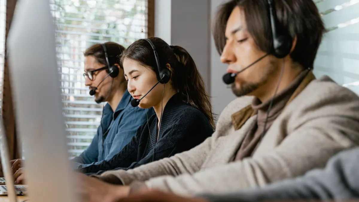 Tres agentes de call center trabajando diligentemente con auriculares en un entorno de oficina, mostrando trabajo en equipo.