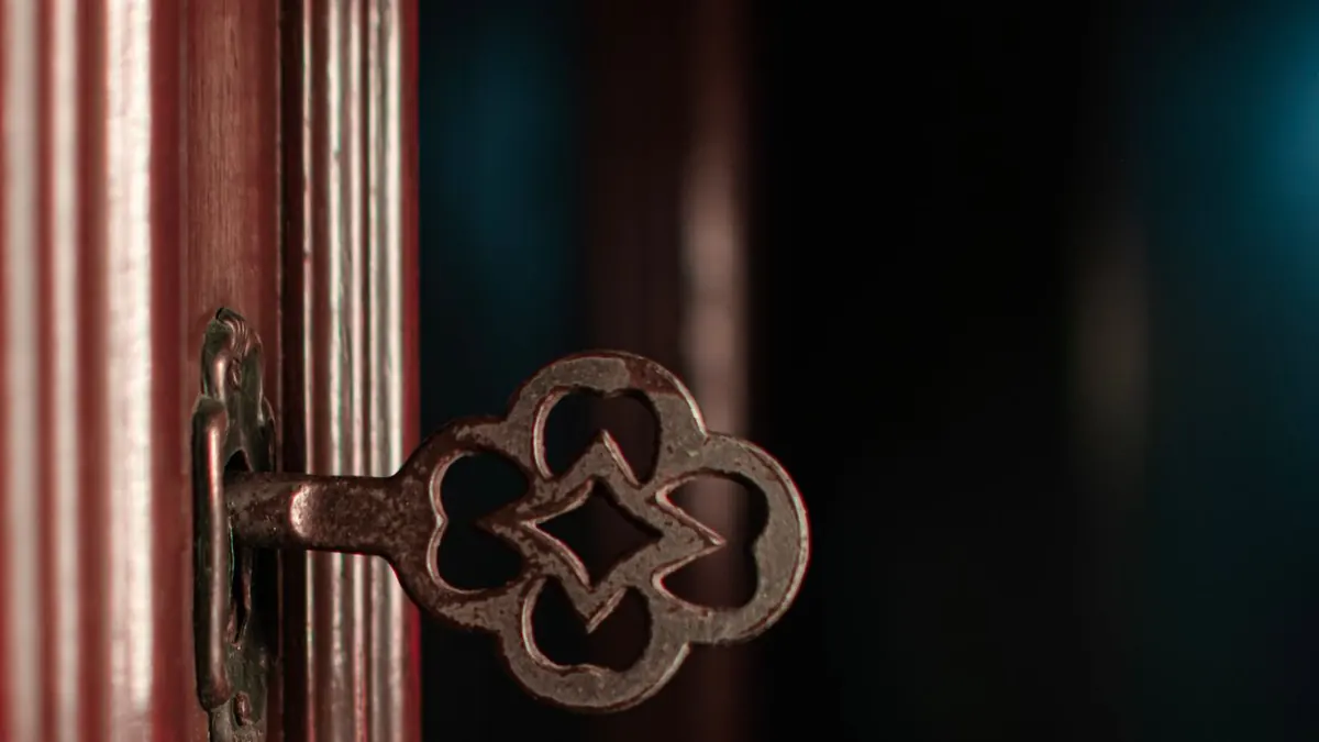 Primer plano de una llave antigua ornamentada en la cerradura de una puerta de madera, creando un ambiente vintage.
