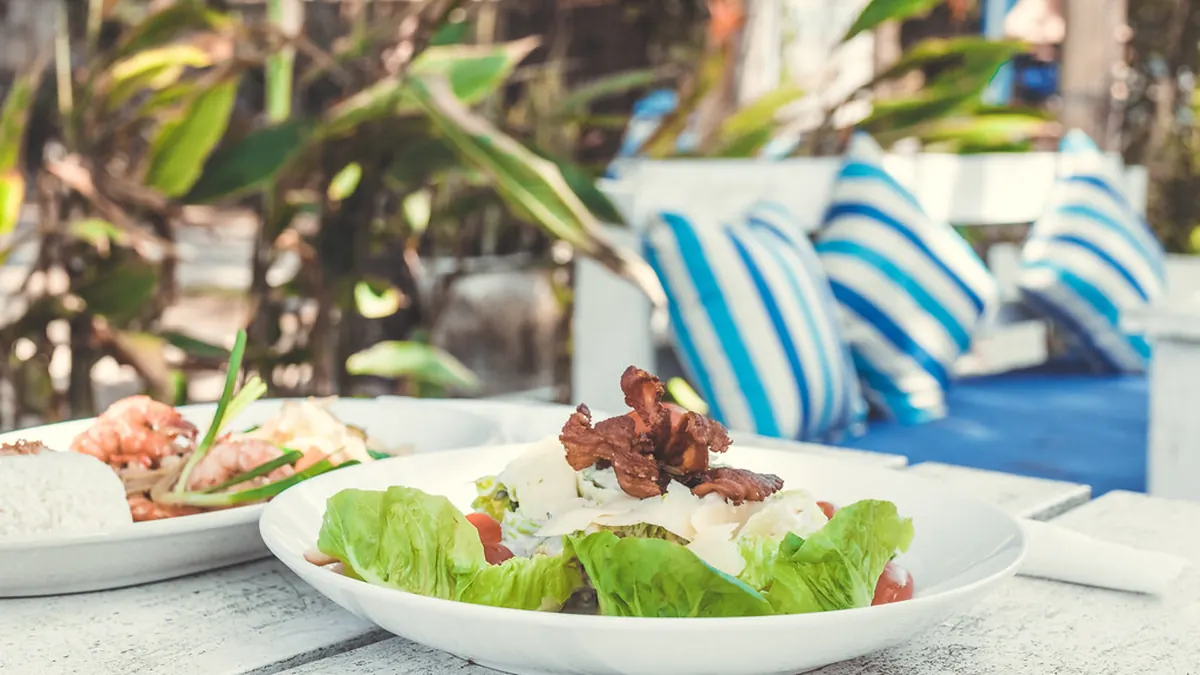 Plato de ensalada y carne servido en una terraza