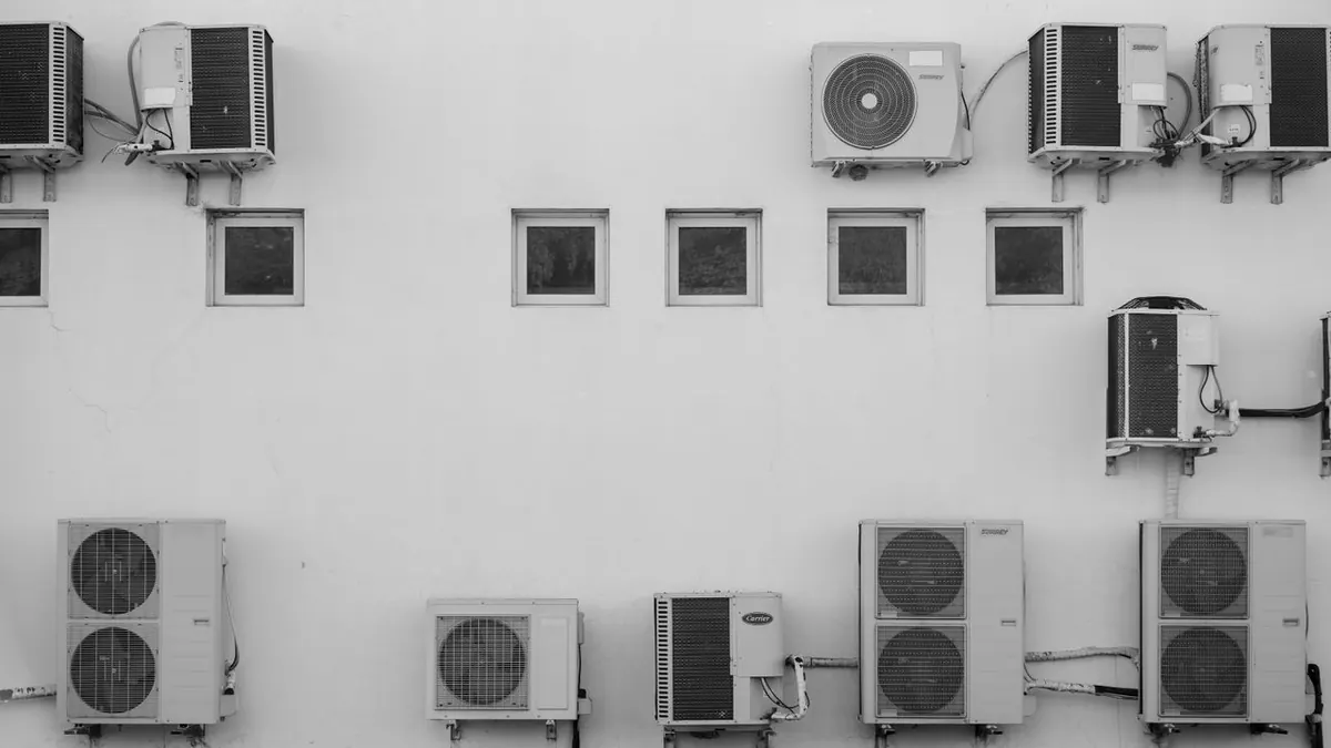 Imagen en blanco y negro de aparatos de aire acondicionado montados en la fachada de un edificio en Córdoba, Argentina.