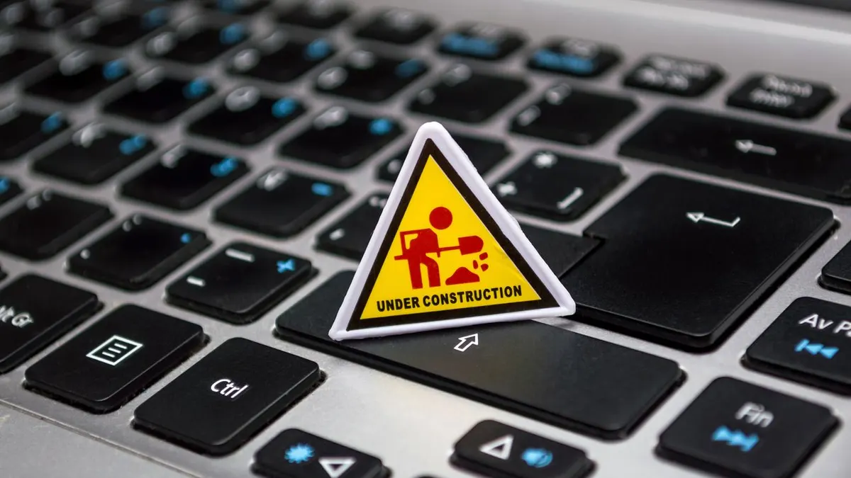 Un pequeño cartel de construcción colocado en un teclado de laptop que simboliza el desarrollo digital.