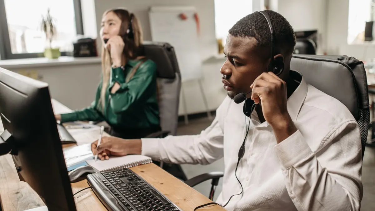 Un equipo enfocado de representantes de atención al cliente trabajando en computadoras y respondiendo llamadas en una oficina