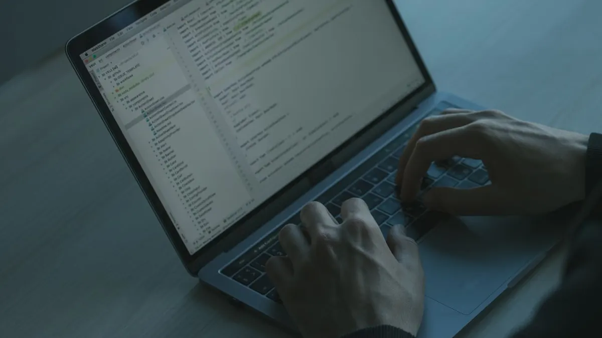Una persona escribiendo código en un portátil con enfoque en ciberseguridad y desarrollo de software.
