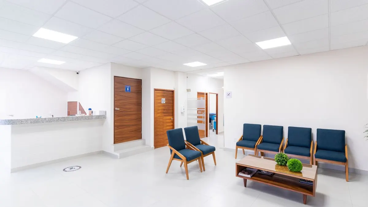 Sala de espera médica brillante y limpia con asientos modernos y decoración.