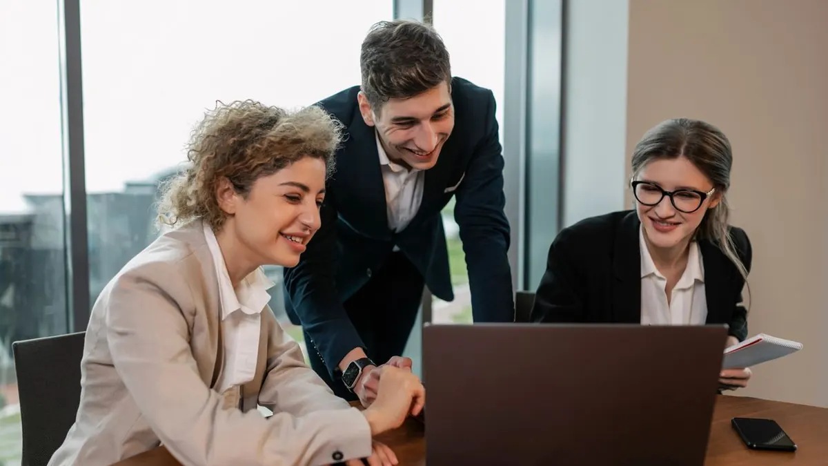 Profesionales de negocios trabajando en equipo en un entorno de oficina moderno, discutiendo proyectos en un portátil.