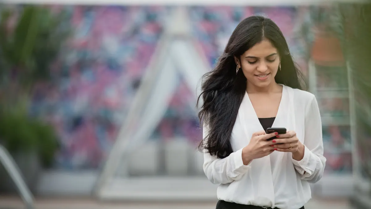 Mujer sonriendo mientras escribe en su móvil