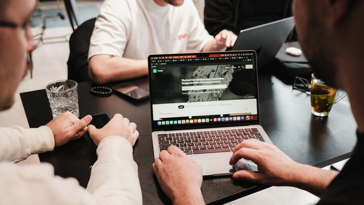 Grupo de colegas colaborando en laptops en una mesa de oficina moderna.