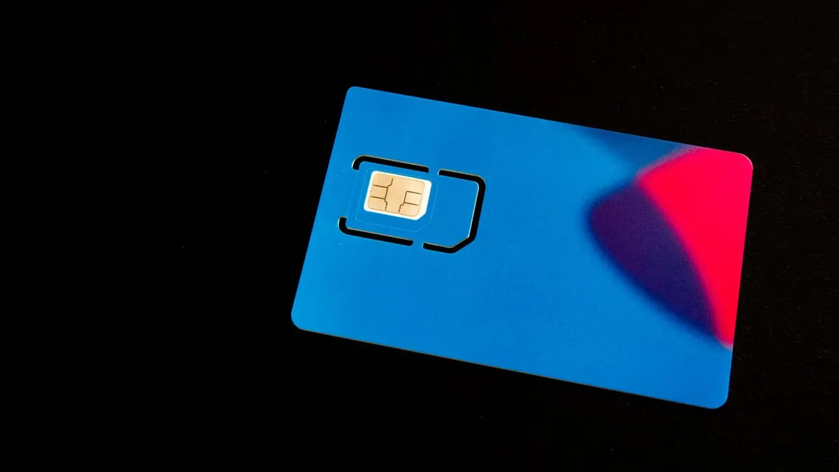 Una tarjeta SIM azul sobre un fondo oscuro con acentos vibrantes en rojo y morado.