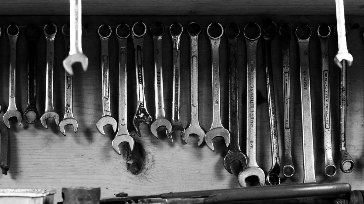Una imagen en blanco y negro de llaves colgadas ordenadamente en una pared de taller.