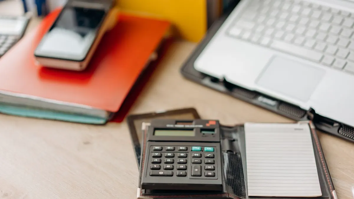 Espacio de trabajo organizado con una calculadora, un bloc de notas y un portátil. Perfecto para temas de productividad.