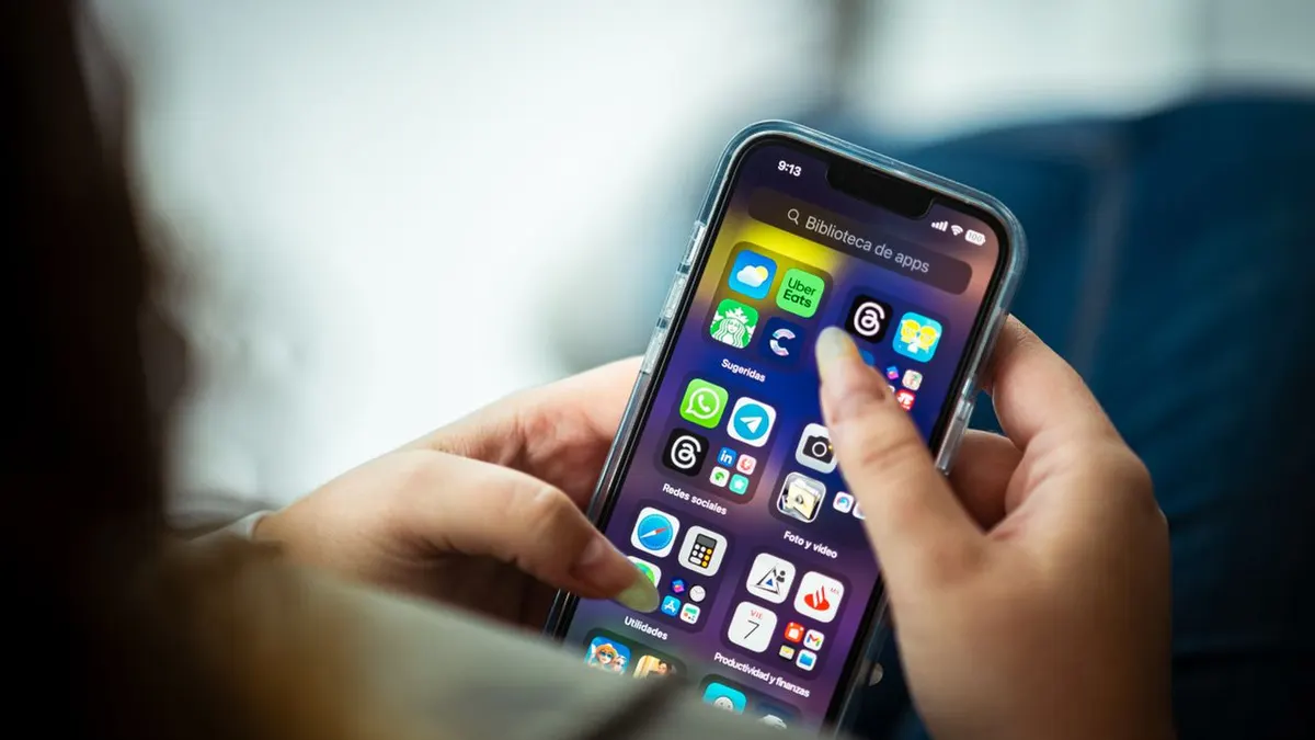 Primer plano de una mujer sosteniendo un teléfono inteligente mostrando varias aplicaciones.